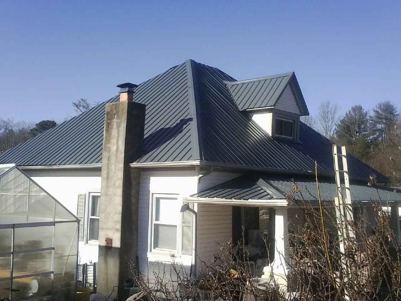 Dark blue standing seam metal roof on a white farmhouse with dormer — Slate & Tile Roof Repair by Roofing Brothers in Dolton