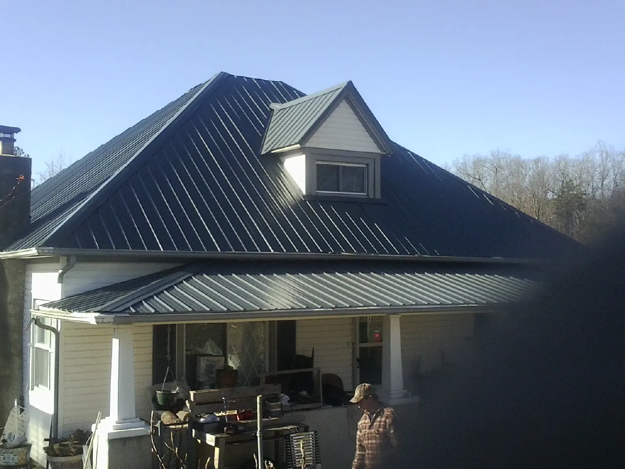 Dark blue standing seam metal roof with a dormer above a front porch in Dolton