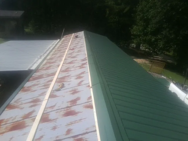 Old rusted panels beside newly installed green metal roofing — Wind Damage Roof Repair by Roofing Brothers in Dolton