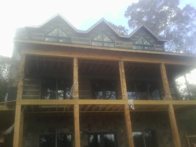 Dormers and porch framing on a large log home under construction — Roof Coating work by our crew in Dolton
