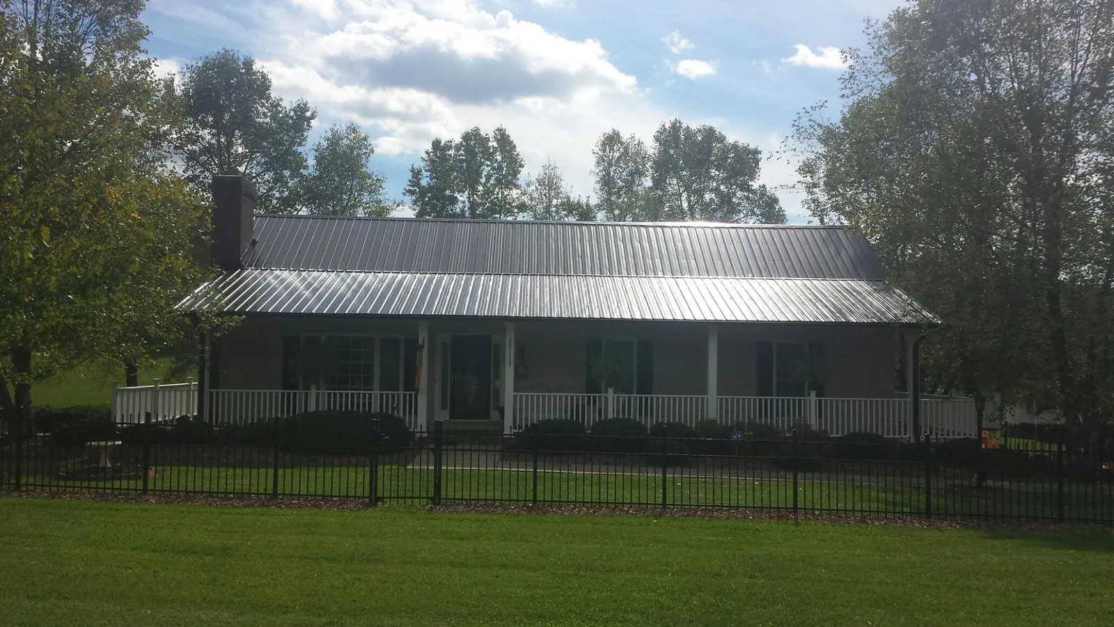 Gray metal roof on a brick ranch with a full width front porch — Gutter Guard Installation work by our crew in Dolton