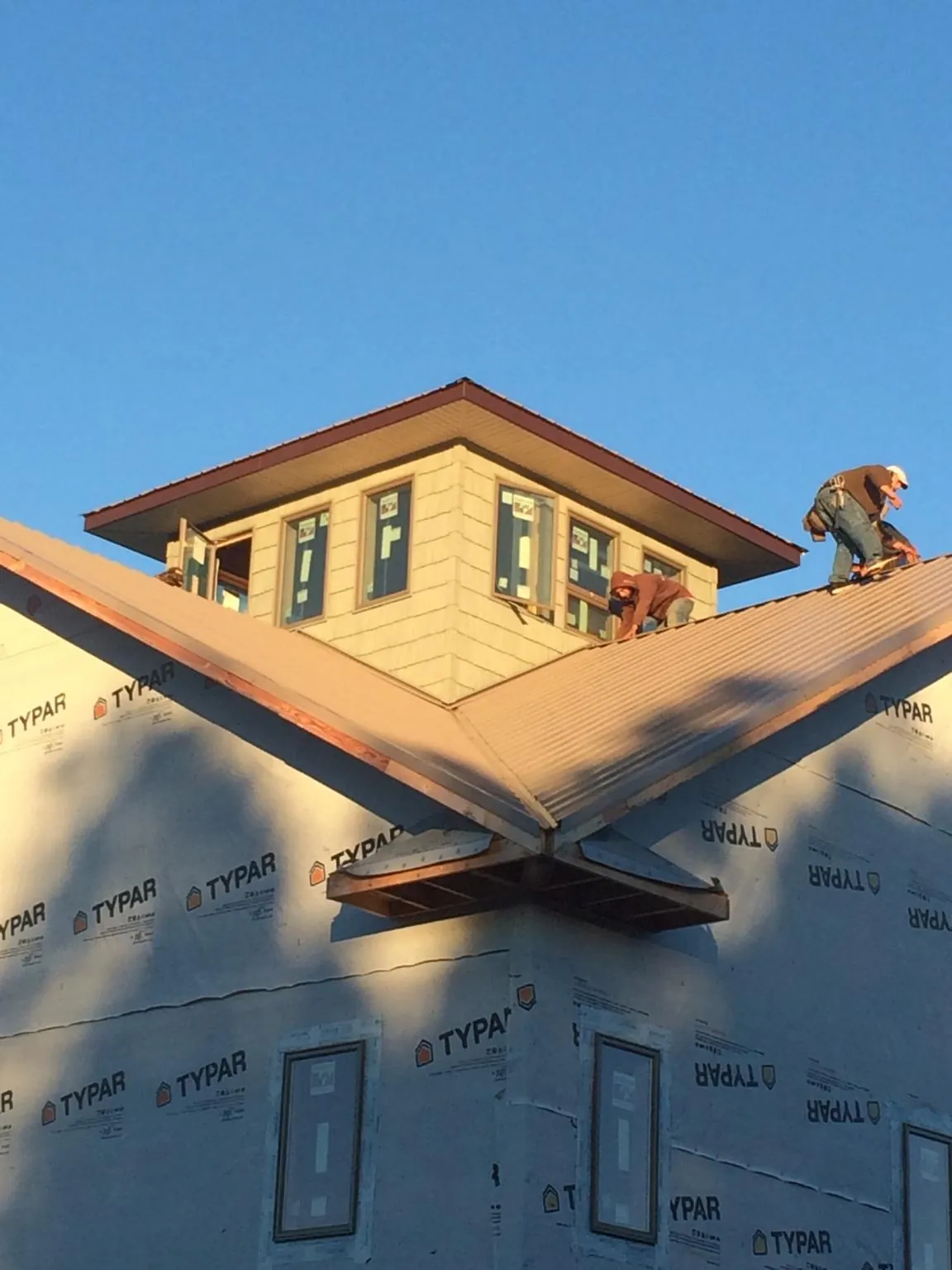 Roofers working around a rooftop cupola on a new metal roof at sunset — Roof Waterproofing in Dolton by Roofing Brothers